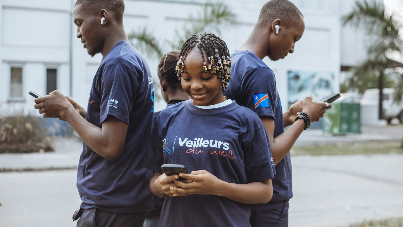 Trois jeunes Veilleurs du Web en train de vérifier des informations sur leurs smartphones