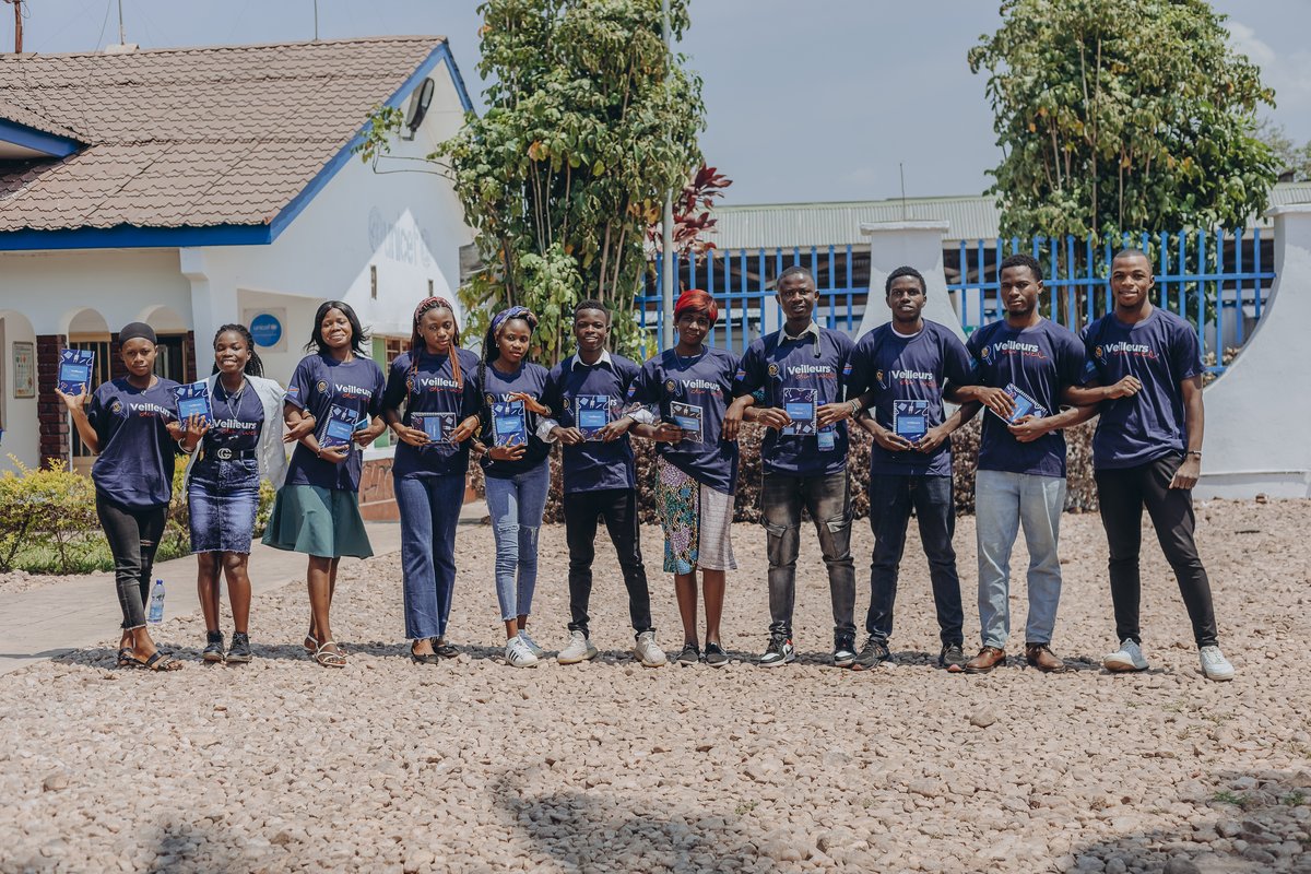Onze Veilleurs du Web alignés devant le bâtiment UNICEF tenant leurs carnets de formation